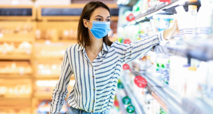 mujer cogiendo un producto de los estantes del supermercado